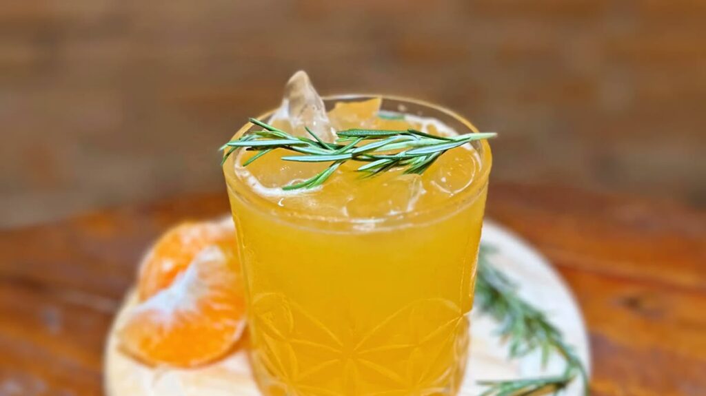 Drink autoral amarelo servido com gelo e alecrim